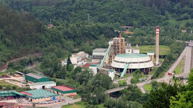 Aerial view of industrial zone with power plant in Asturian green mountain landscape, Spain. impact of heavy industry on climate and air quality