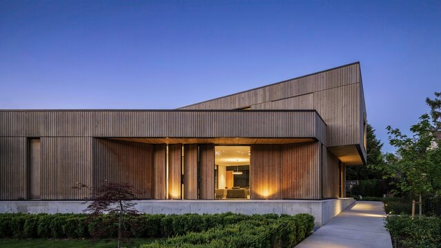 Residence with modern timber cladding features a minimalist architectural design illuminated at dusk for a luxury aesthetic.
