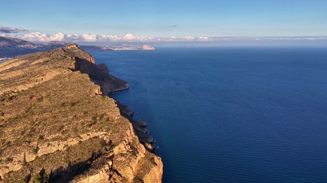 Azure coastline with steep rocky cliffs, coastal ecologist mapping habitats from drone, clear deep blue water,