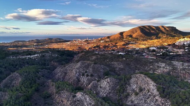 Golden hillside town aerial at sunset, travel photographer scouting rural village and rocky cliffs under warm