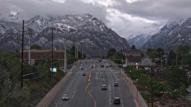 Flying backwards over East 9000 South Street traffic in Sandy Utah with Gorgeous snow covered Wasatch Mountains