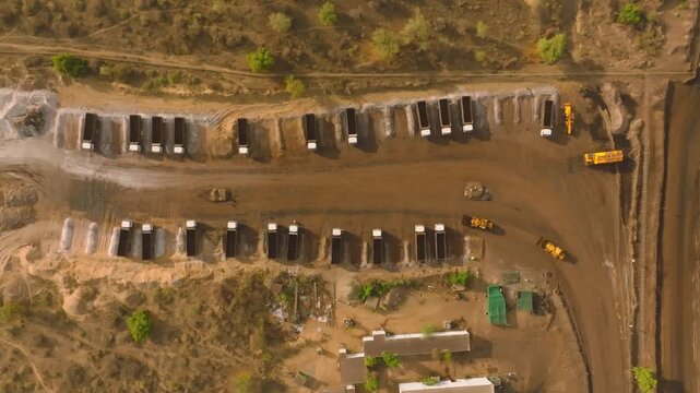 Overhead aerial - two rows of dump trucks and yellow machinery at Thar mine yard