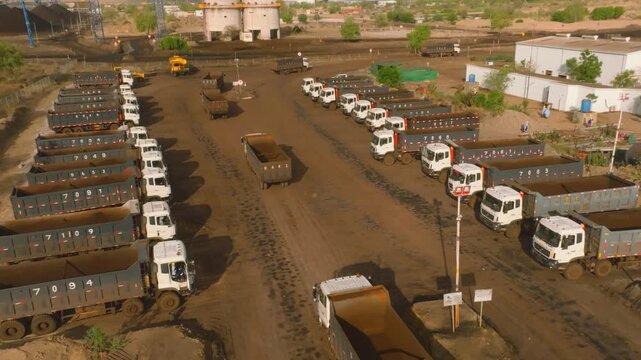 Aerial - rows of numbered white dump trucks loaded with coal at Thar mine yard