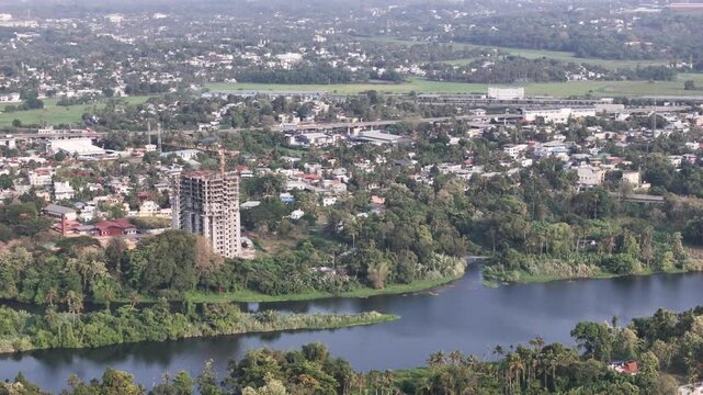 Drone video of riverfront landscape of Aluva, featuring a residential tower under construction, dense tropical greenery, and the serene Periyar River flowing through the heart of the region.