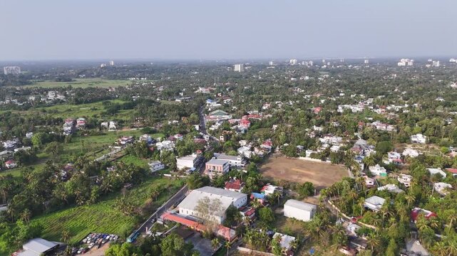 Wide aerial view of Aluva featuring dense tropical greenery, scattered residential developments, and expansive open spaces, highlighting the tranquil suburban and cricket ground.