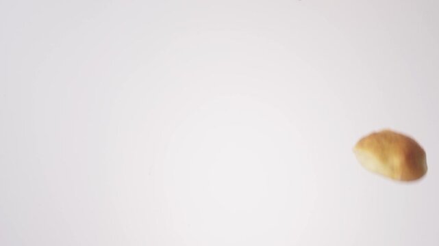 Golden savory kolaches raining down on white seamless backdrop in cinematic slow motion. texas bakery branding, game day appetizer reels, party finger food content.