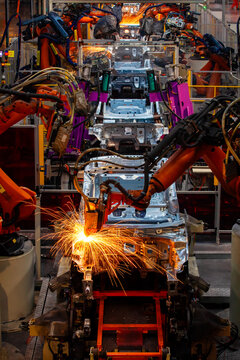Robotic arms are welding body weld points on an automated production line at an automobile factory.