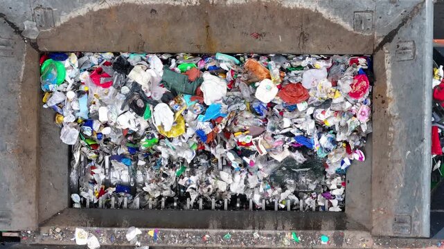 Plastic waste is loaded into a processing machine at a recycling facility. Sorting and recovery systems operate to separate recyclable materials. Procedures involve mechanical processing.