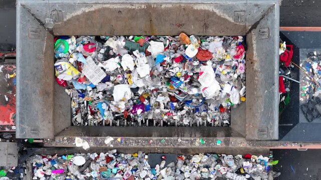 Plastic waste enters a sorting and recovery system. Machines separate recyclable materials from non-recyclable items. The facility focuses on waste management and resource recovery.