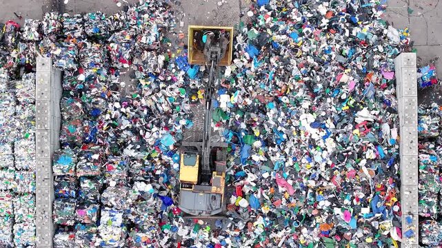 Workers sort and process plastic waste at a recycling facility. Machines separate recyclable materials from non-recyclable materials for proper disposal and recycling.