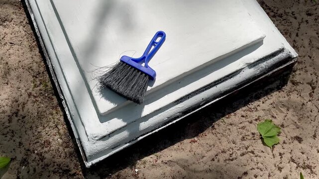 Cleaning and preparing repaired concrete grave border before painting in cemetery