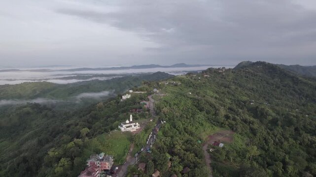 Wide drone view of Sajek Valley ridge, mosque, and clouds in Bangladesh