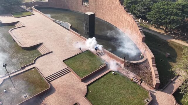 Drone view of smoke drifting across the red brick memorial plaza and pool