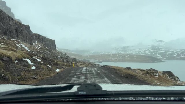 POV Of Driver Driving On An Icy Road Alongside A Fjord In Djupavik, Iceland.