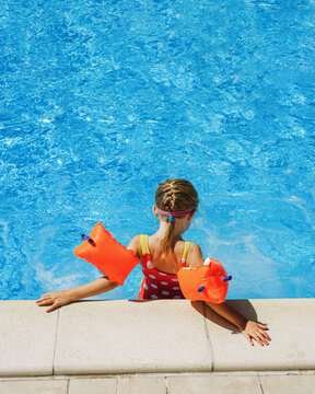 Pool vacation in summer by the sea -  Child in swimming pool on ring toy. Kids swim.  Poster with copy space.