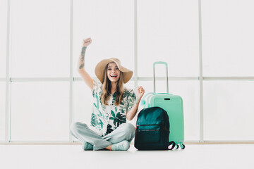 Young woman excitedly anticipating her travel with suitcase and backpack in bright airport terminal