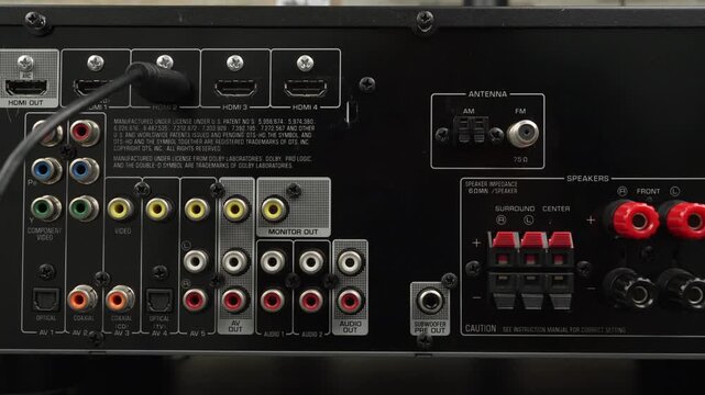 Macro view of an AV receiver rear panel with one HDMI cable plugged in among labeled analog and digital connectors.