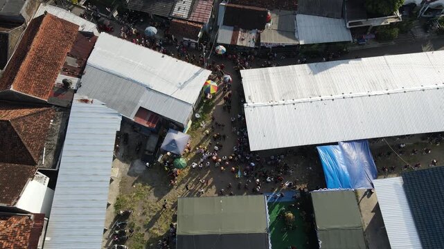 Aerial footage of a cultural procession or Javanese traditional festival, amidst the density of urban villages.