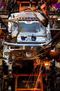 Robotic arms are welding body weld points on an automated production line at an automobile factory.
