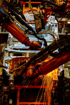 Robotic arms are welding body weld points on an automated production line at an automobile factory.