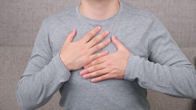 Adult holding the chest due to discomfort, chest pain, or possible heart-related symptoms. Concept of cardiovascular health, heart attack warning signs, medical emergency, healthcare.