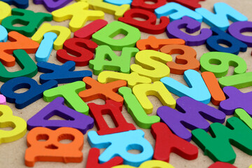 Fototapeta premium Colorful plywood alphabet letters scattered across a brown background, forming a vibrant educational pattern ideal for learning, literacy, preschool activities, and creative design.