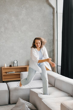 Energetic Woman Having Fun Jumping on Couch