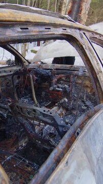 Crashed and burned out car wreck on snowy roadside reckless driving vertical video.