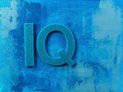 IQ letters made from textured material on an abstract blue painted background with copy space, representing intelligence quotient, cognitive ability, education, psychology, learning, knowledge.