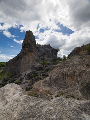 Fototapeta premium Limestone formations in Surat Thani Province, Thailand, featuring sharp, distinctive landscapes surrounded by sparse vegetation against a backdrop of a cloudy sky.