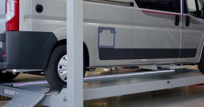Delivery van parked on a modern hydraulic platform lift inside a service garage