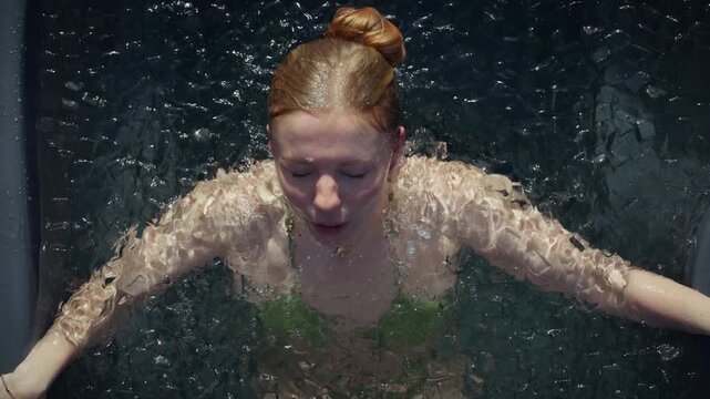 Woman in ice bath practicing cold plunge breathing for recovery and wellness indoors