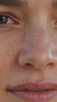Vertical video: Glancing woman leaning forward, camera moving closer in studio, revealing freckles