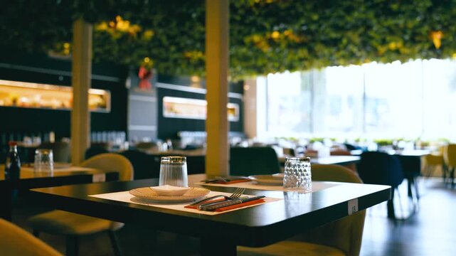 Empty tables set for service in a modern and elegant japanese sushi restaurant. Refined interior with a green ceiling and cozy lighting