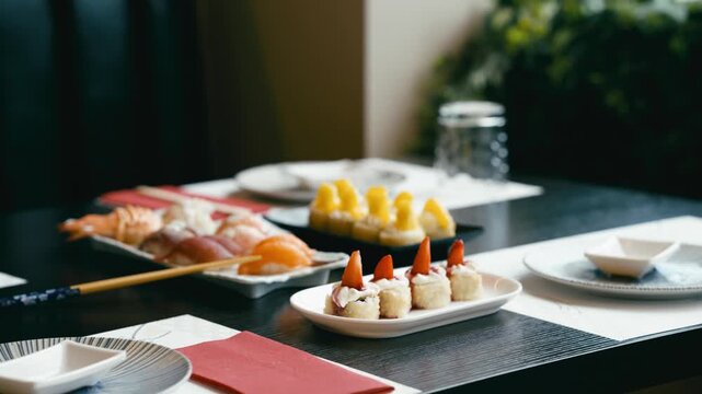 Plates of various colorful sushi rolls and nigiri set on a dark table. Japanese cuisine at an all you can eat buffet restaurant