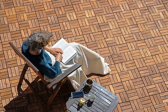 erkner, deutschland - eine frau liest auf ihrem balkon ein buch