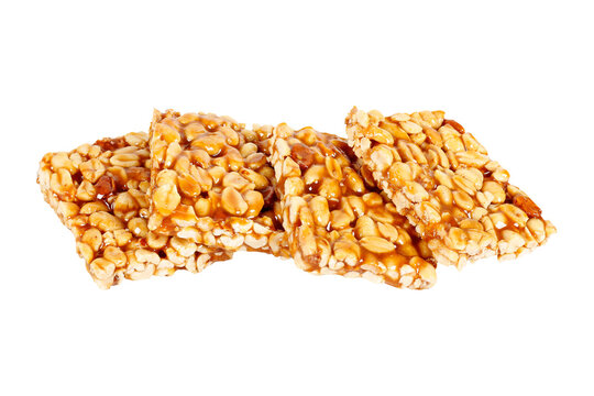 Four traditional Brazilian pe de moleque pieces made with caramelized peanuts, stacked and isolated against a white background