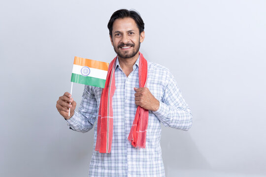 young man with aPortrait of a indian rural man holding Indian Flag on Independence or republic day, standing isolated on gray studio background rms crossed