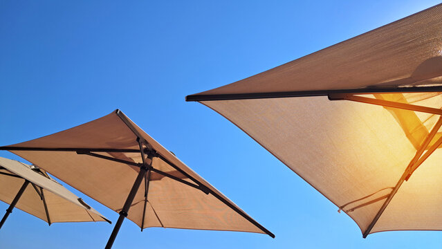 Sunlit patio umbrellas against blue sky