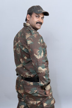 Portrait of confident indian army soldier in uniform standing by looking at camera with copy space isolated on gray studio background 