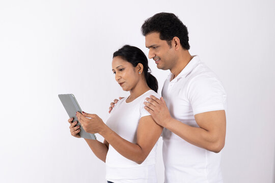 Indian happy young couple using ipad isolated on
white studio background