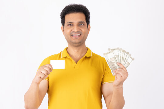 Portrait of a young Indian man showing credit card and currency note on white background.
