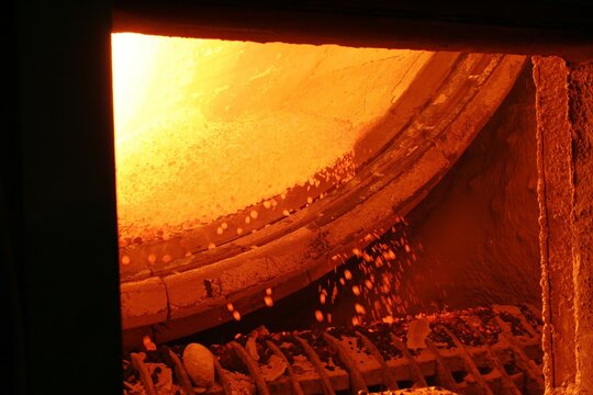 Hot pellets being discharged from rotary kiln at approximately 1000 degrees Celsius during pyrometallurgical processing of mineral ore in industrial alloy of metal production
