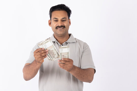 Portrait of a Indian young man showing counting indian rupees on white background.