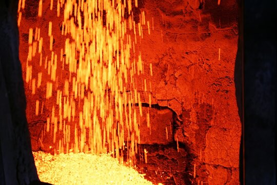 Hot pellets being discharged from rotary kiln at approximately 1000 degrees Celsius during pyrometallurgical processing of mineral ore in industrial alloy of metal production