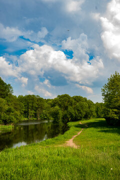 A calm river winding through a green meadow under a blue sky. Ideal for slow life meditative wallpapers, eco-friendly lifestyle branding, and peaceful nature backgrounds.