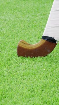 Slow motion hockey player, stick and ball on artificial turf.
