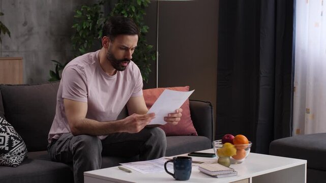 Stressed man calculating bills and expenses at home