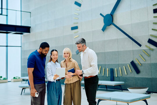 Professional team of diverse colleagues collaborating and sharing information on a digital tablet in a contemporary office setting