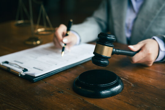 Judge's gavel and scales of justice with a lawyer reviewing documents, symbolizing law, justice, legal services, and court proceedings.